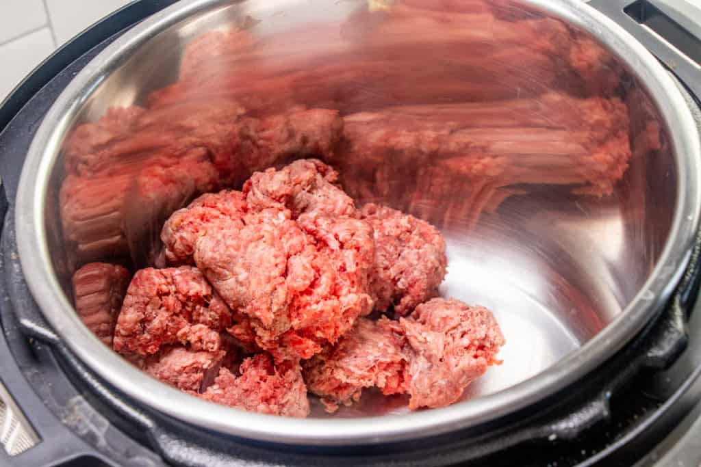 uncooked ground beef in the bottom of the insert of an electric pressure cooker