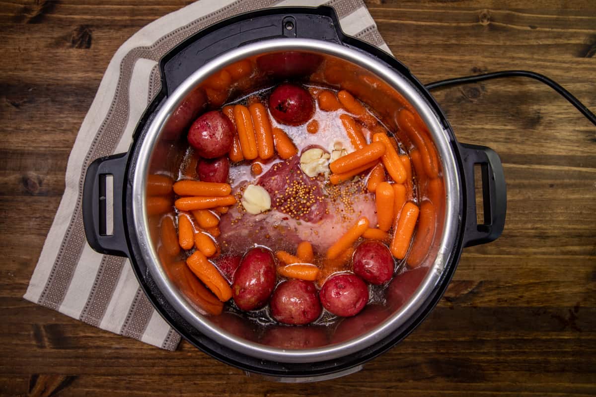 seasoned carrots and potatoes placed around brisket in 6-quart Instant Pot.