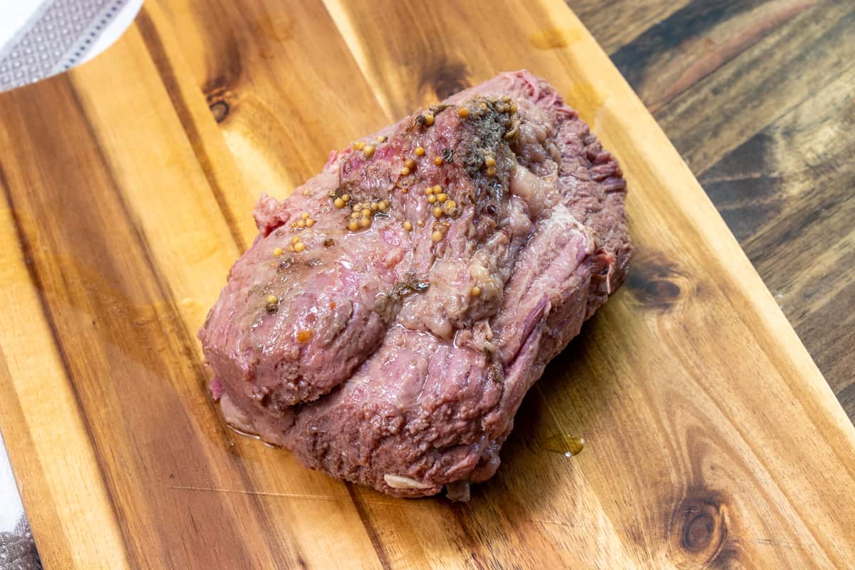 fully cooked corned beef resting on a cutting board.