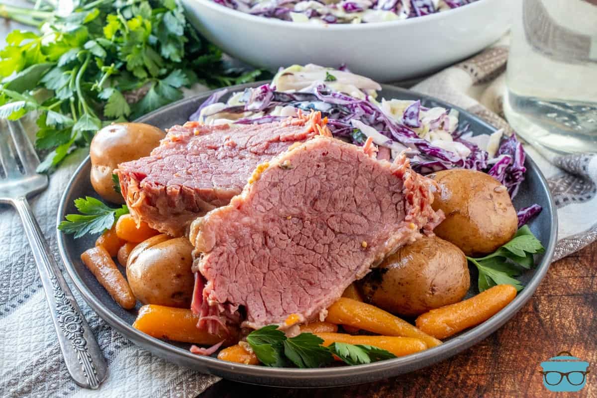 Instant Pot Corned Beef on a plate with potatoes and carrots and Cole slaw.