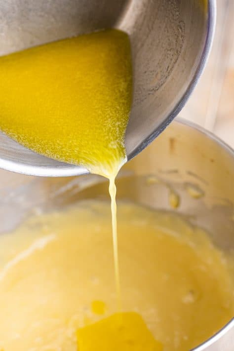 butter being poured into cinnamon roll cake batter.