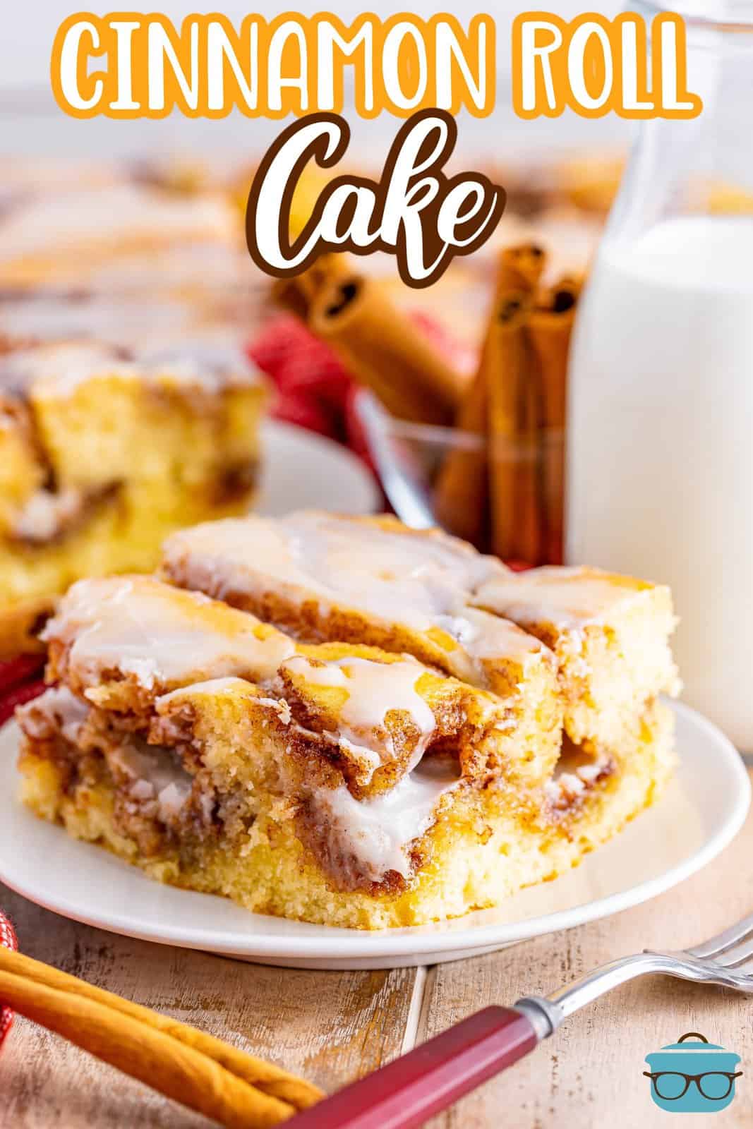 a slice of cinnamon roll cake on a white plate with a small bottle of milk in the background.