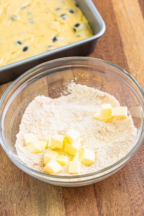 cubed butter added to crumble topping mixture in a small bowl.
