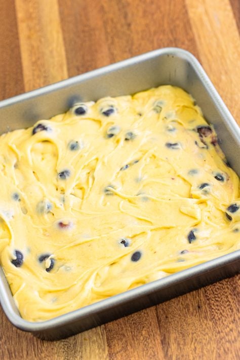 blueberry buckle batter spread into a cake pan.