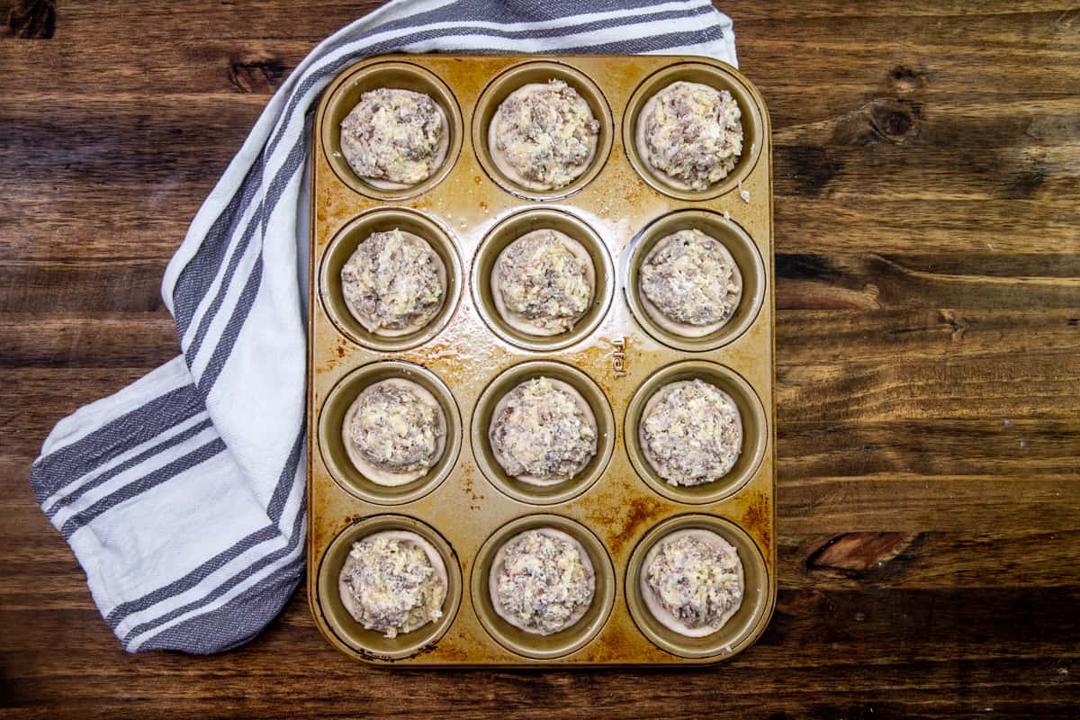 cream cheese sausage mixture added to the tops of each refrigerated biscuit in a muffin tin.