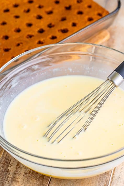 A whisk in a bowl of cheesecake pudding.