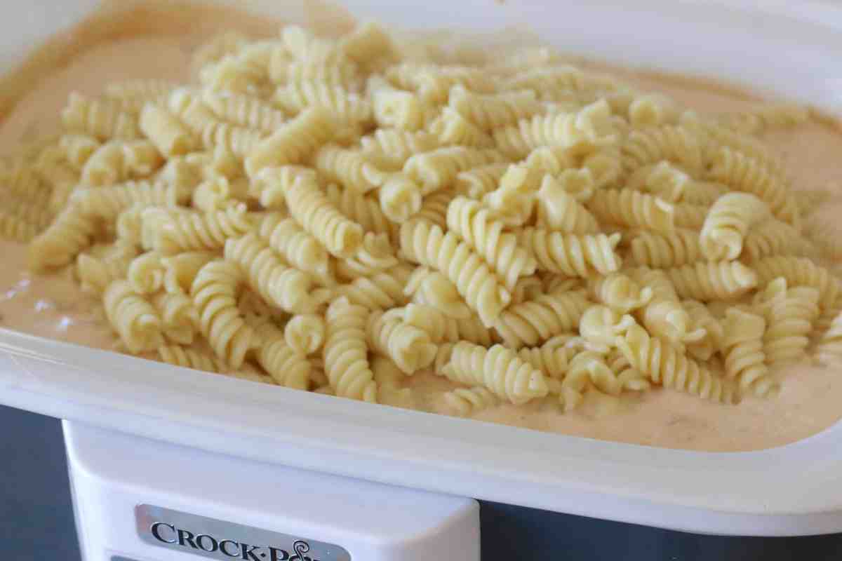 cooked rotini pasta added to slow cooker.