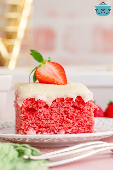 A slice of Easy Strawberry Cake with cream cheese frosting and a sliced strawberry.