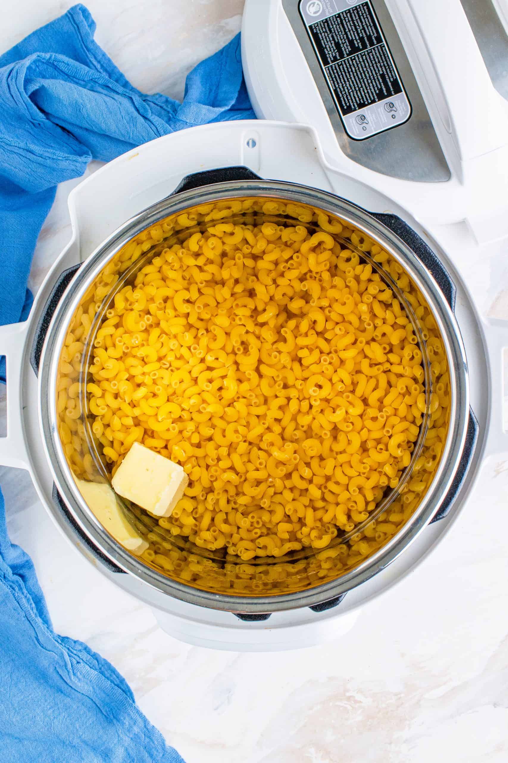 macaroni noodles, butter and water in the bottom of an Instant Pot electric pressure cooker.