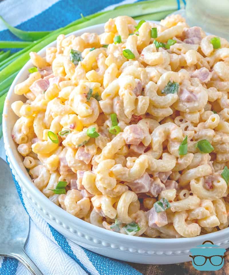 Ham and Cheese Macaroni Salad served in a large white bowl and topped with sliced green onions.