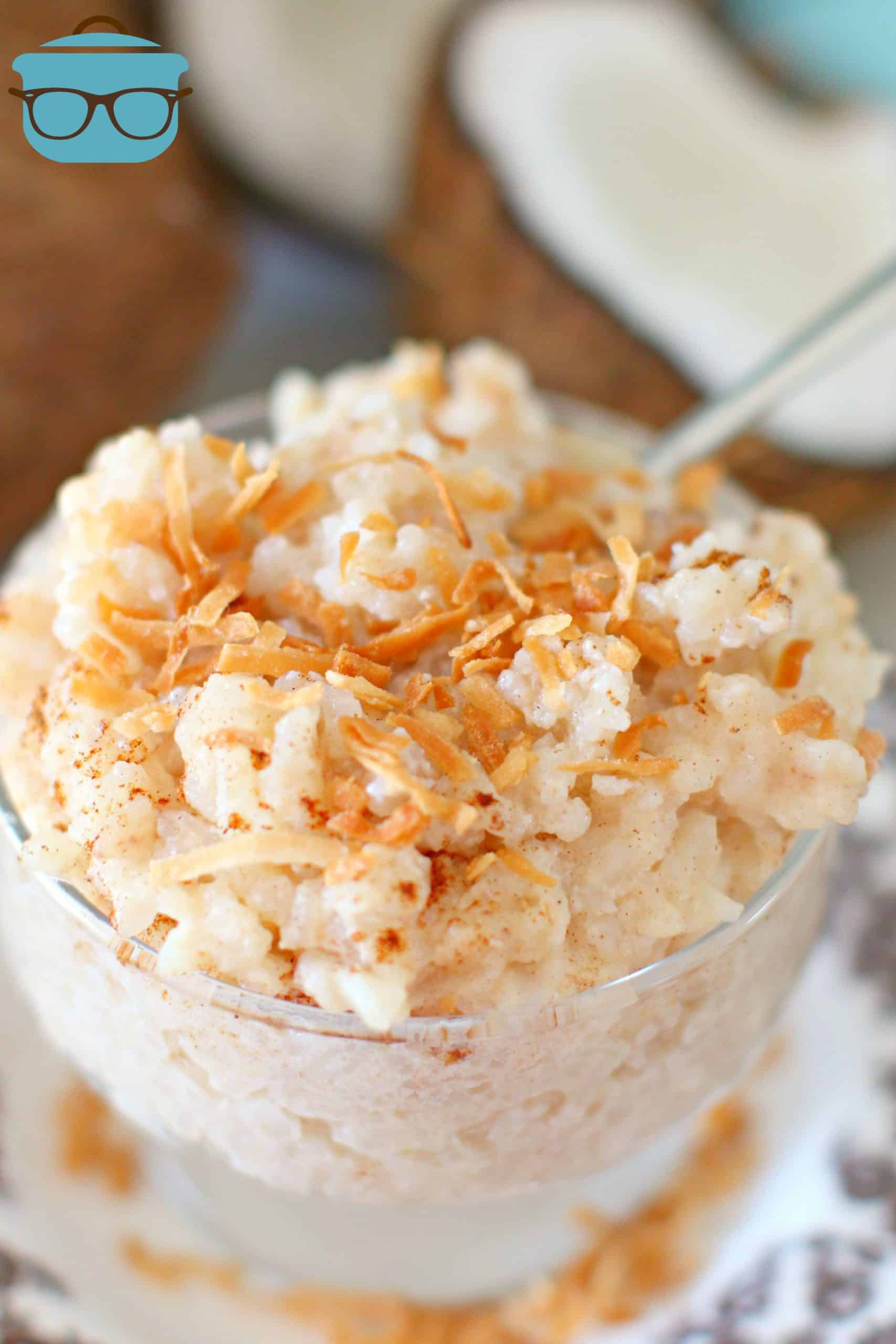 closeup photo of Coconut Rice Pudding in a clear glass pudding bowl topped with toasted flaked coconut. 