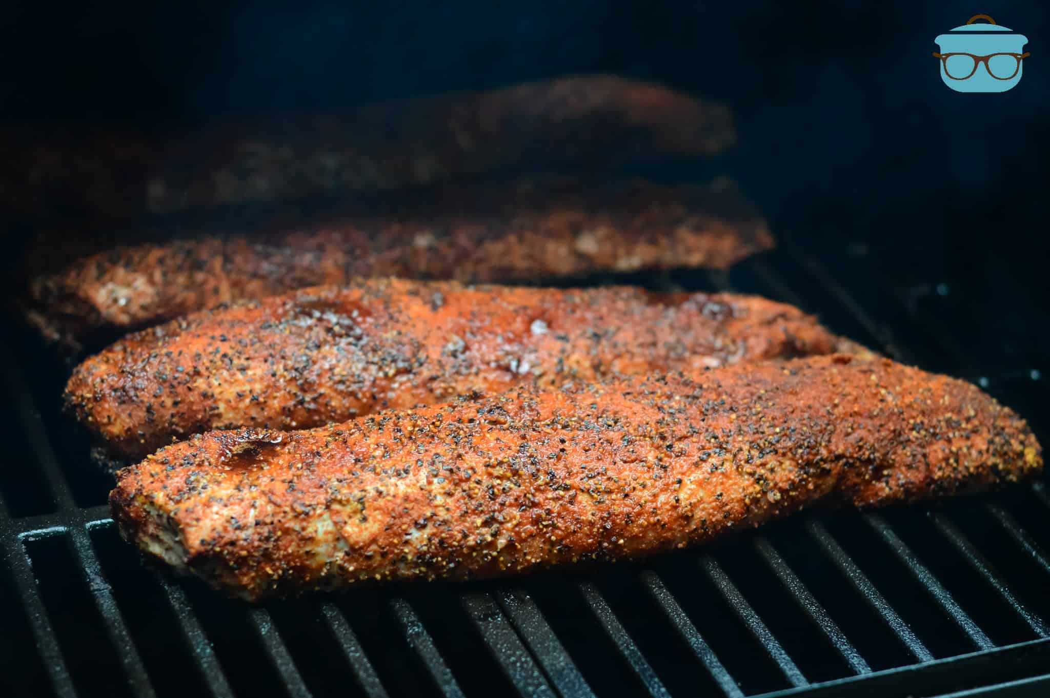 four pieces of seasoned potk tenderloing being smoked on a grill.