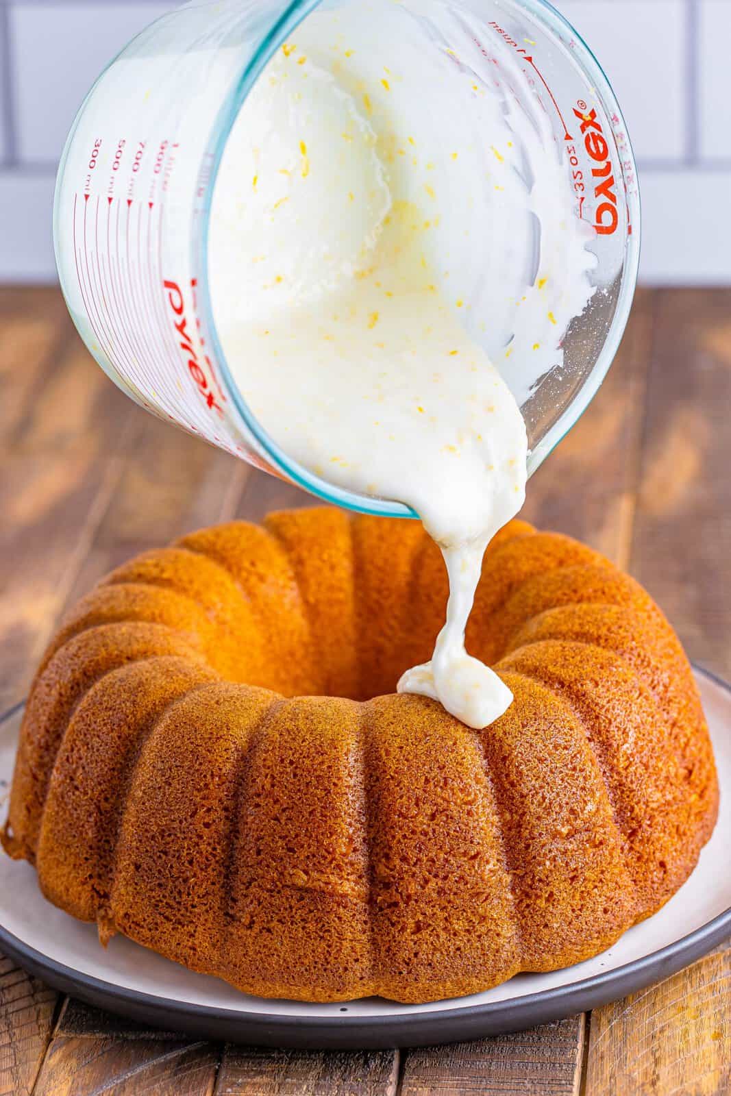 pouring icing over 7up bundt cake on a white plate. 