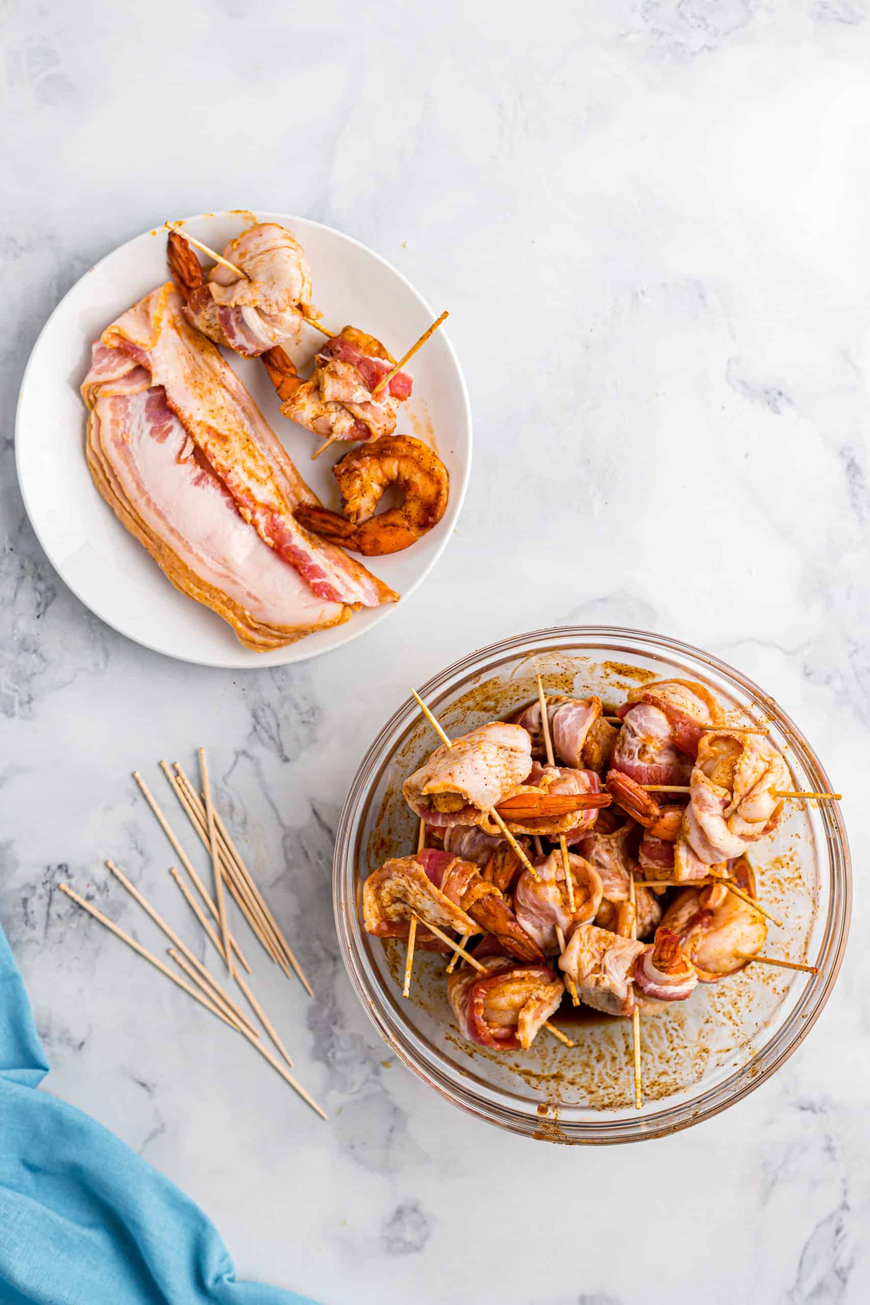 wrapping seasoned shrimp with slices of bacon and skewered with toothpicks.