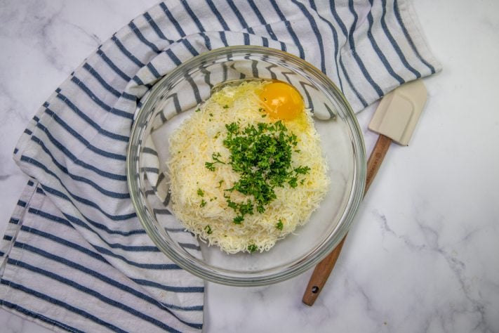 Cottage cheese, parmesan cheese, egg and parsley stirred together in a bowl.