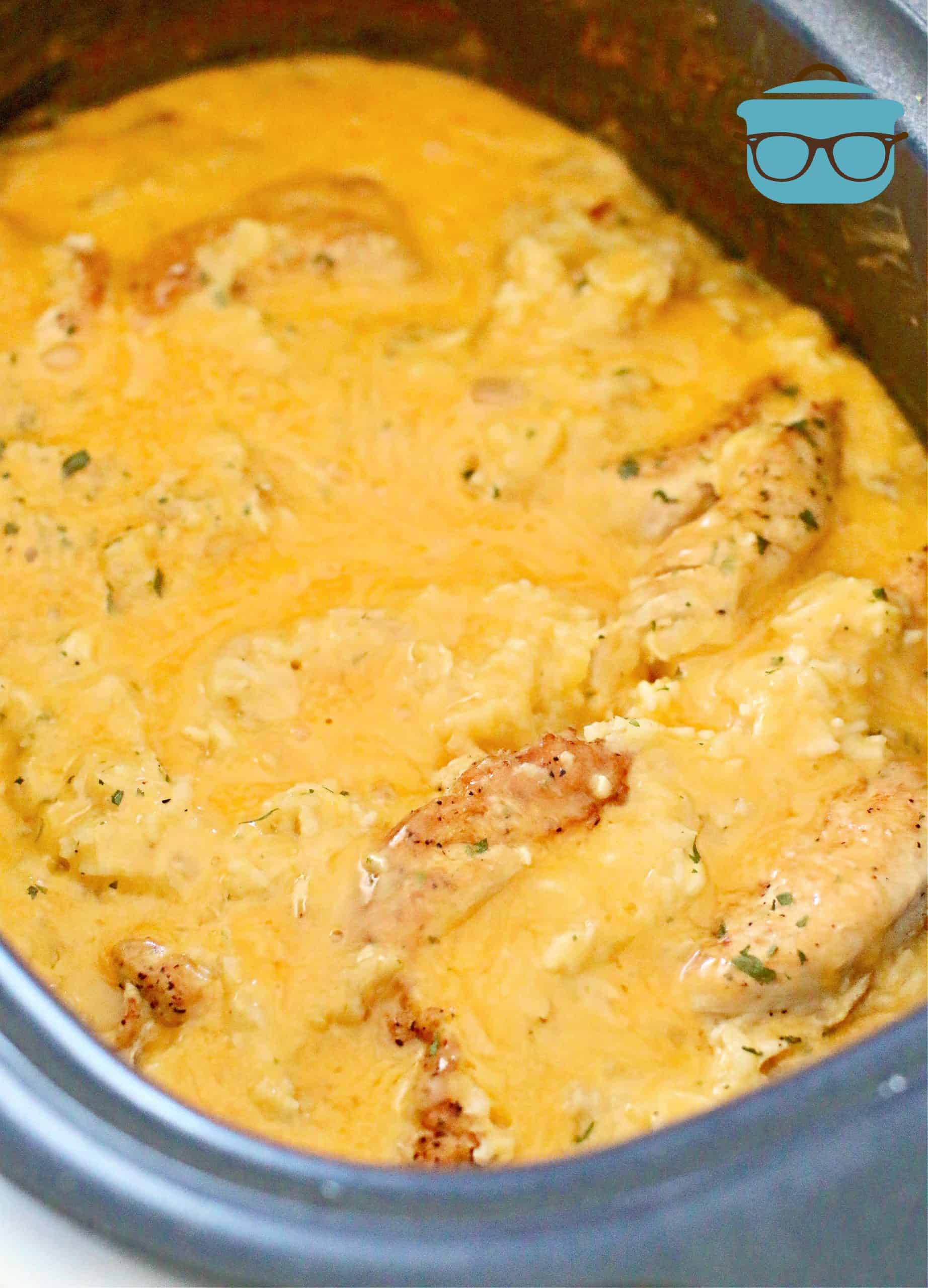 melted cheese shown over chicken and rice in slow cooker.