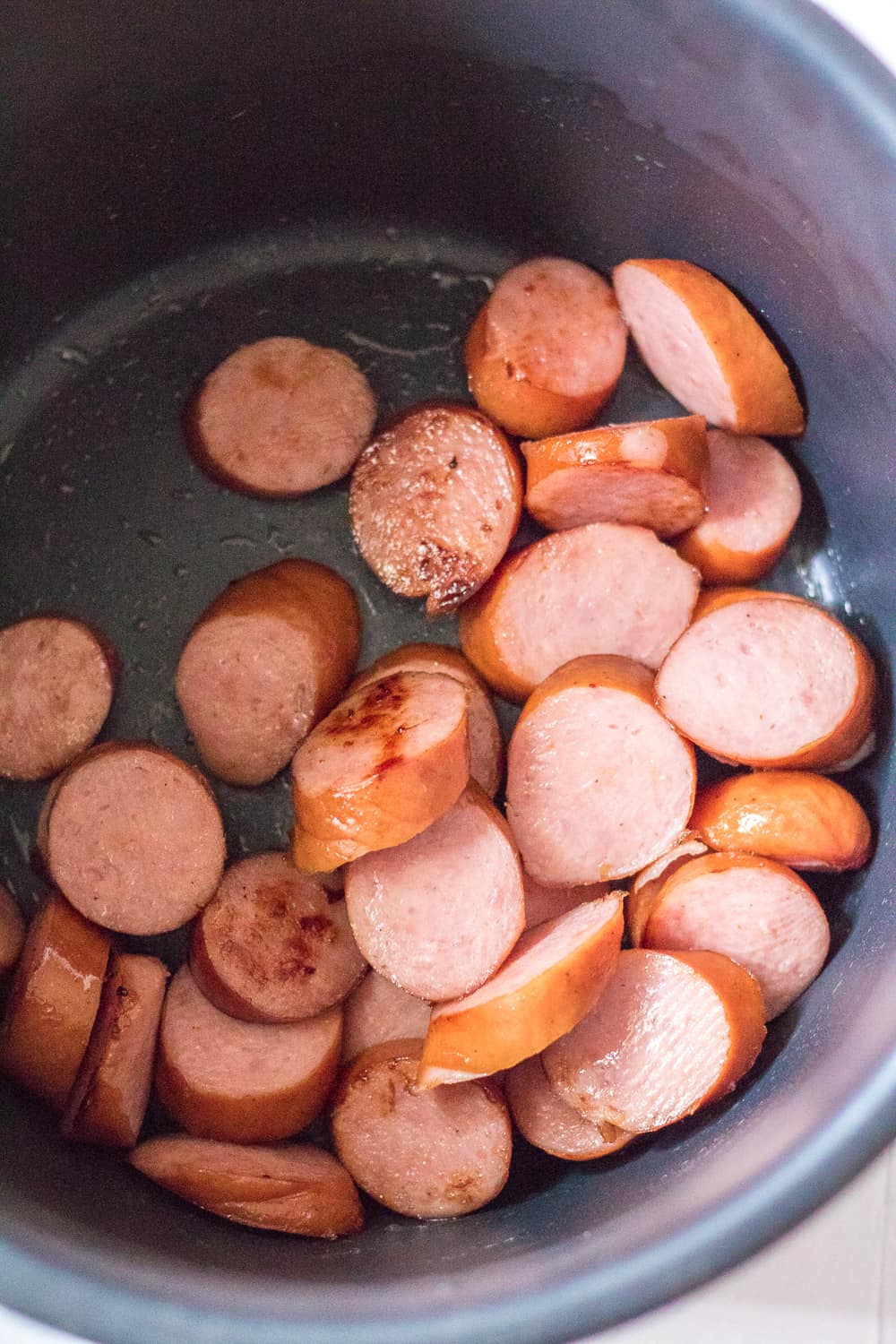 browning sliced sausage in the bottom of an Instant Pot.
