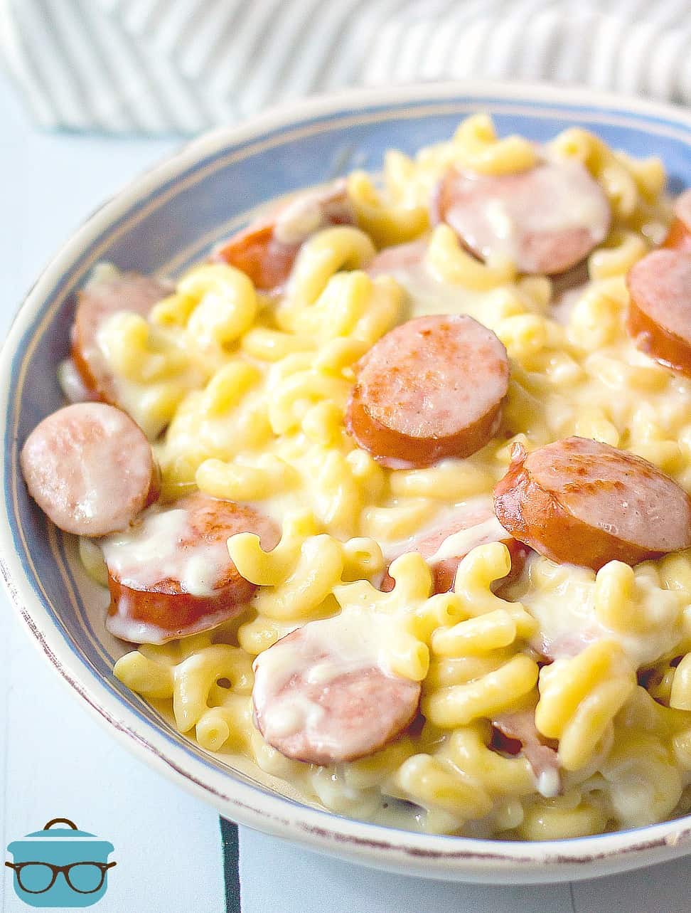 Sausage Macaroni and Cheese in a bowl with a dish towel on the side.