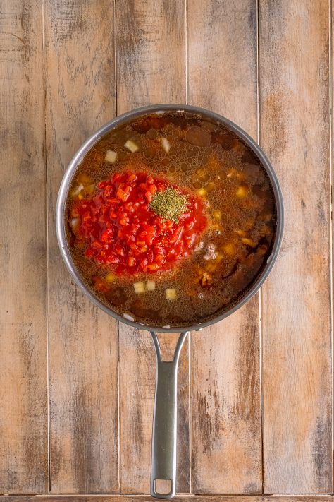beef broth and Italian diced tomatoes and Italian seasoning added to large skillet with ground beef.
