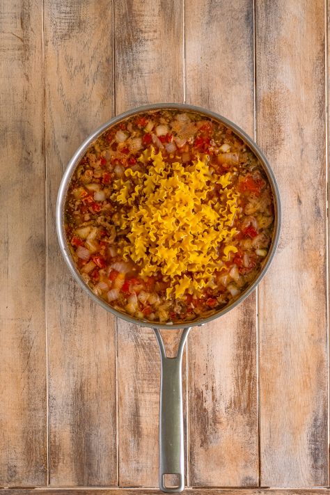 uncooked Mafalda pasta added to large skillet.