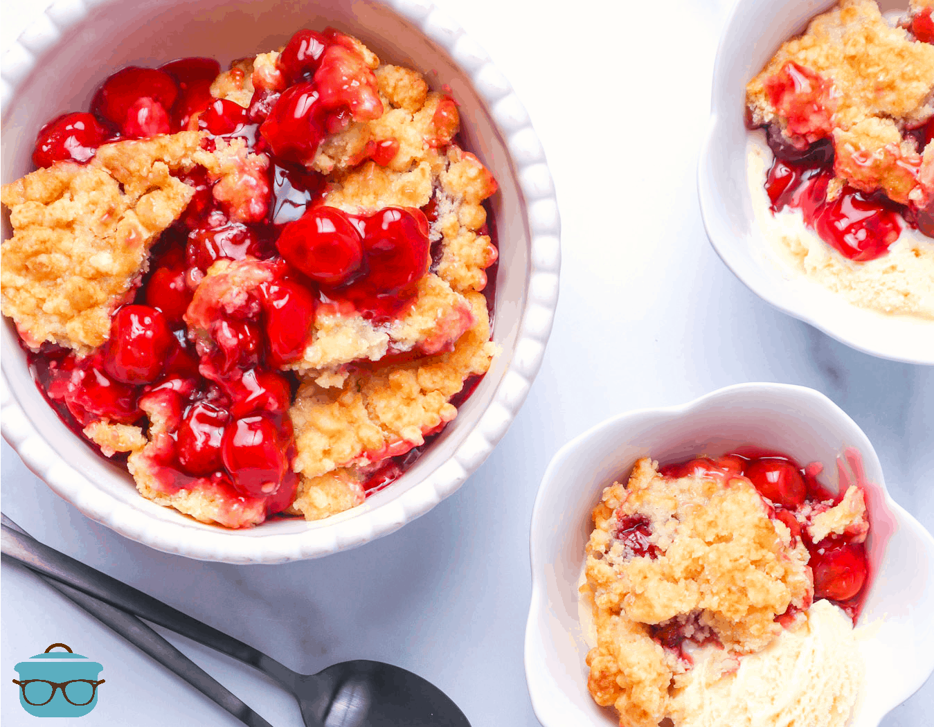 pictured, cherry cobbler served in three white bowls and scoops of vanilla ice cream.