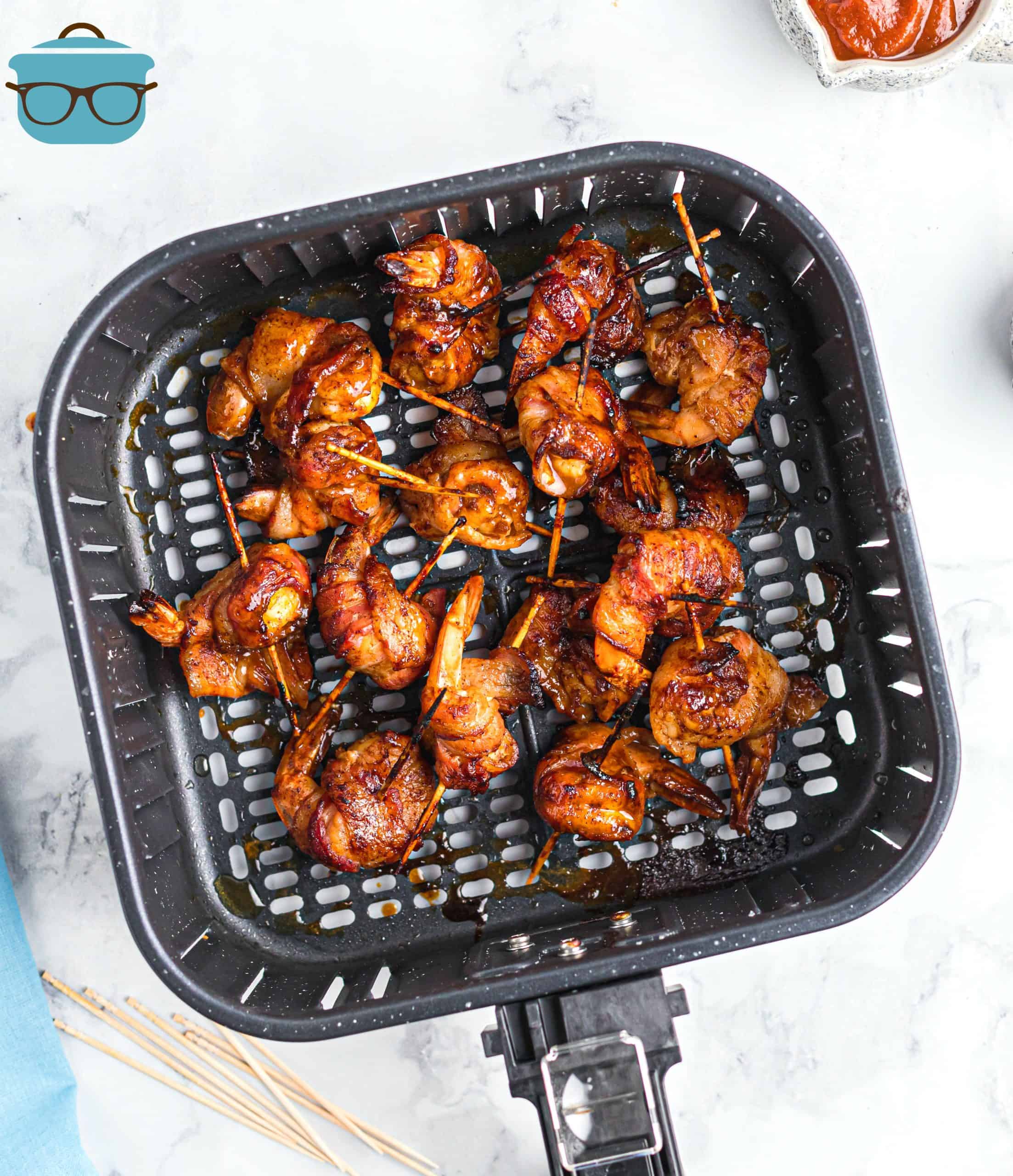 cooked bacon garlic shrimp shown in an air fryer basket.
