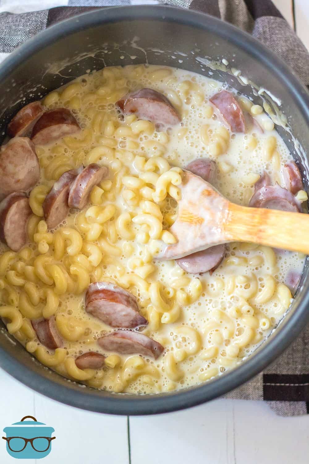 stirring macaroni and cheese and sausage together.