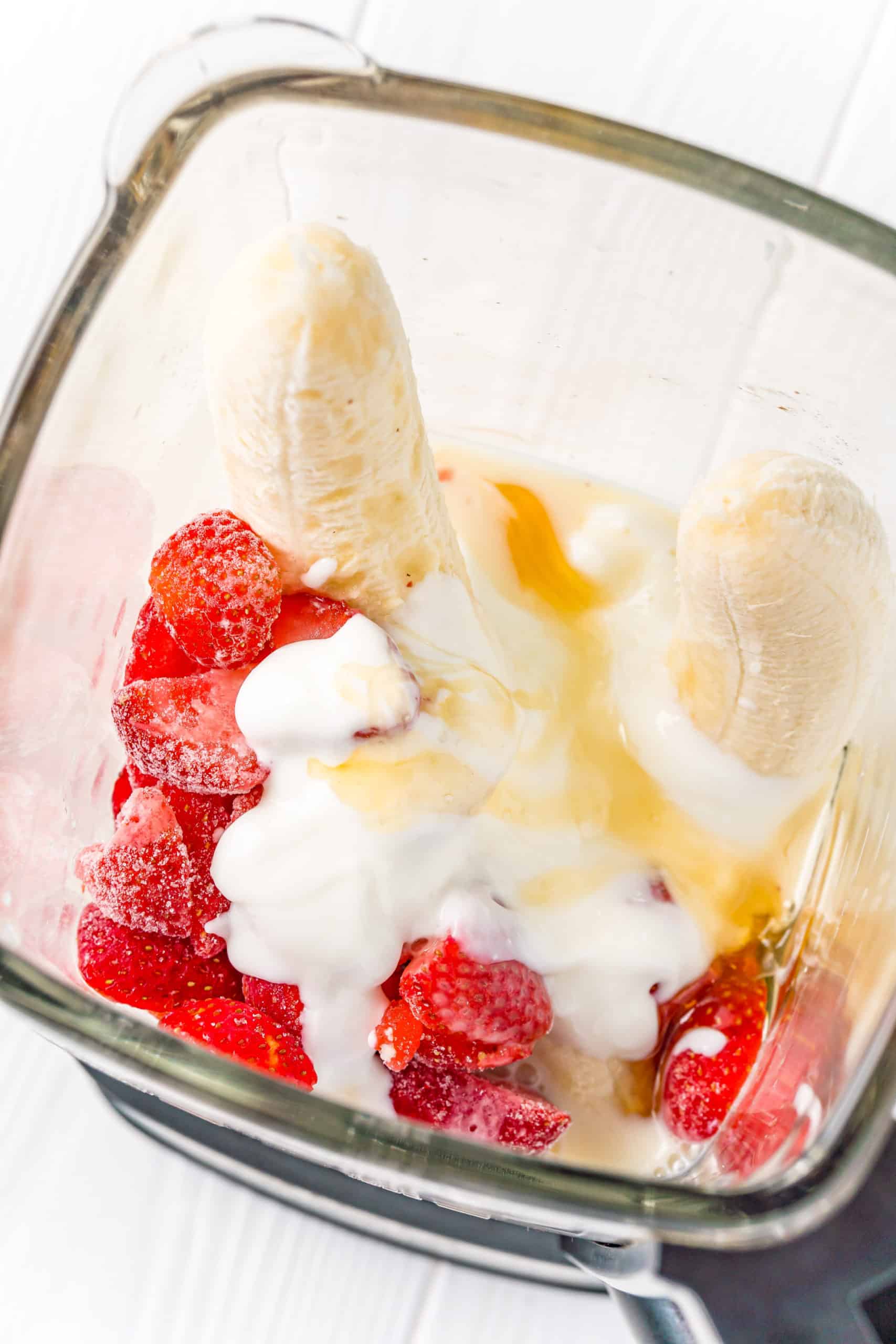 strawberry banana smoothie ingredients added to a blender.