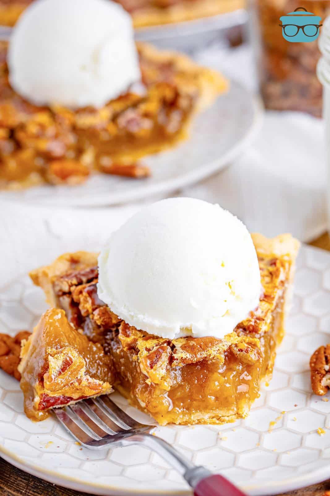 a slice of southern pecan pie on a white plate and topped with a scoop of ice cream. 