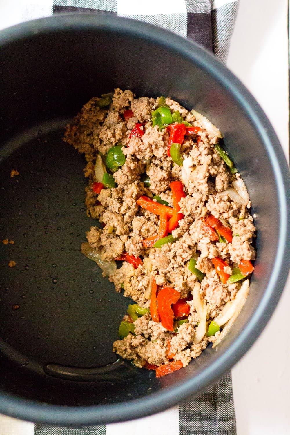 fully cooked ground beef, peppers and onions in the bottom of an instant pot insert.