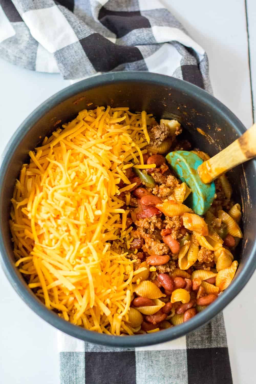 shredded cheddar cheese added to fully cooked taco pasta in the instant pot pressure cooker insert bowl.