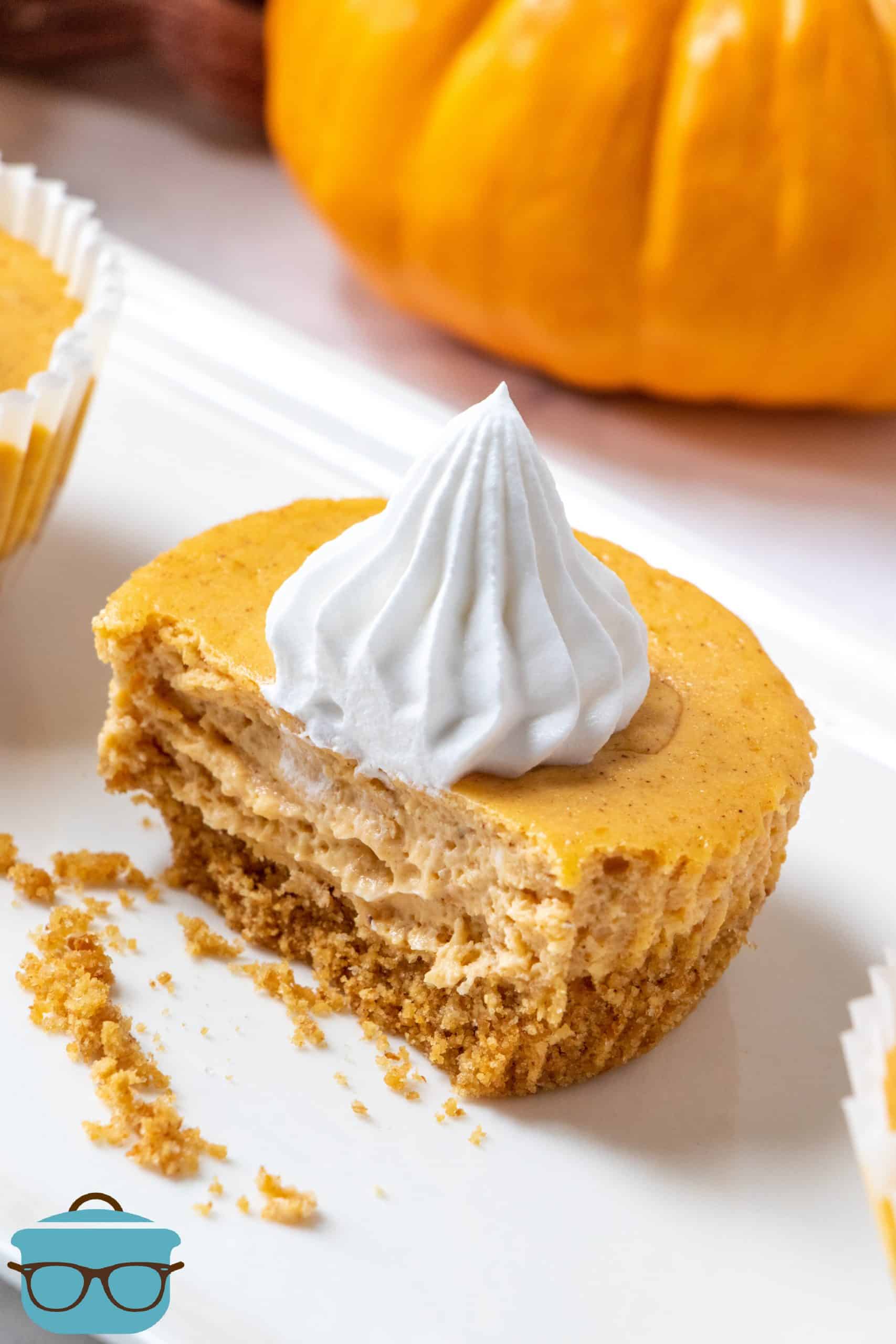 mini pumpkin cheesecakes, a single cheesecake shown on a white platter with a bite removed.