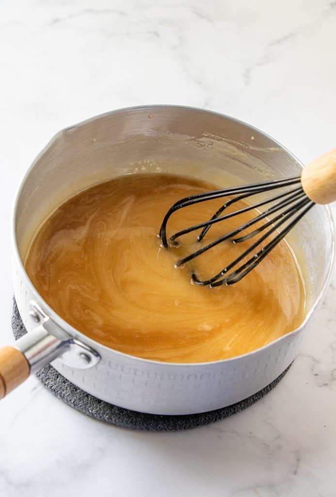whisking vanilla into caramel in a sauce pot