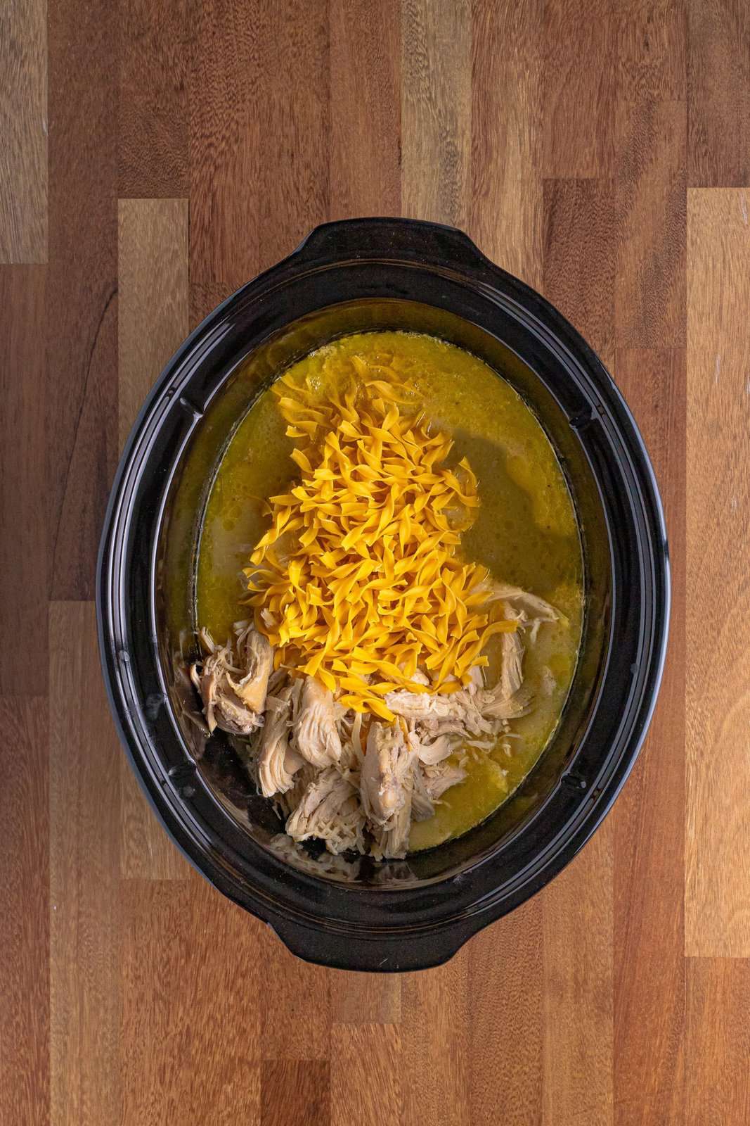 shredded chicken and egg noodles put into slow cooker. 