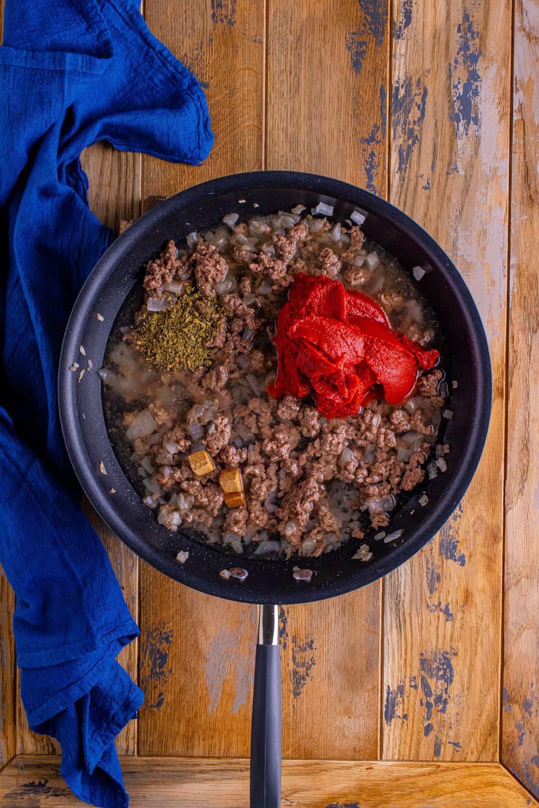 tomato sauce, oregano and beef bouillon cubes added to ground beef in pan.