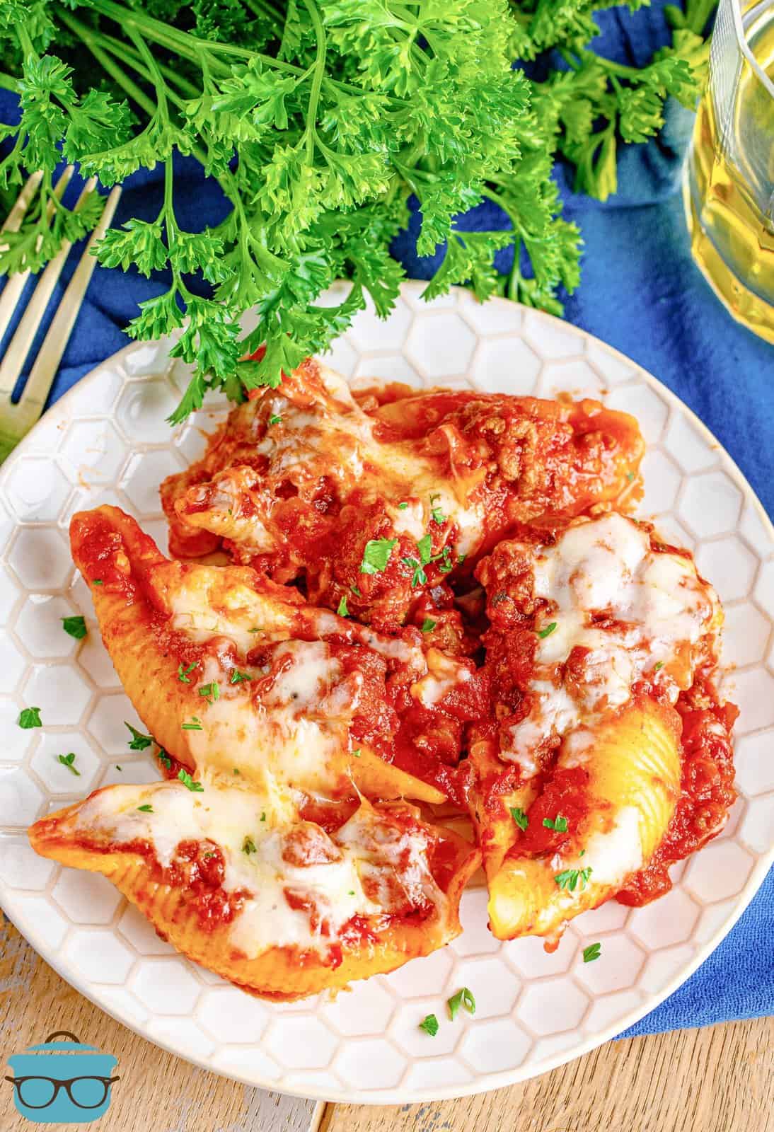 stuffed shells shown on a white plate with some fresh parsley in the background.