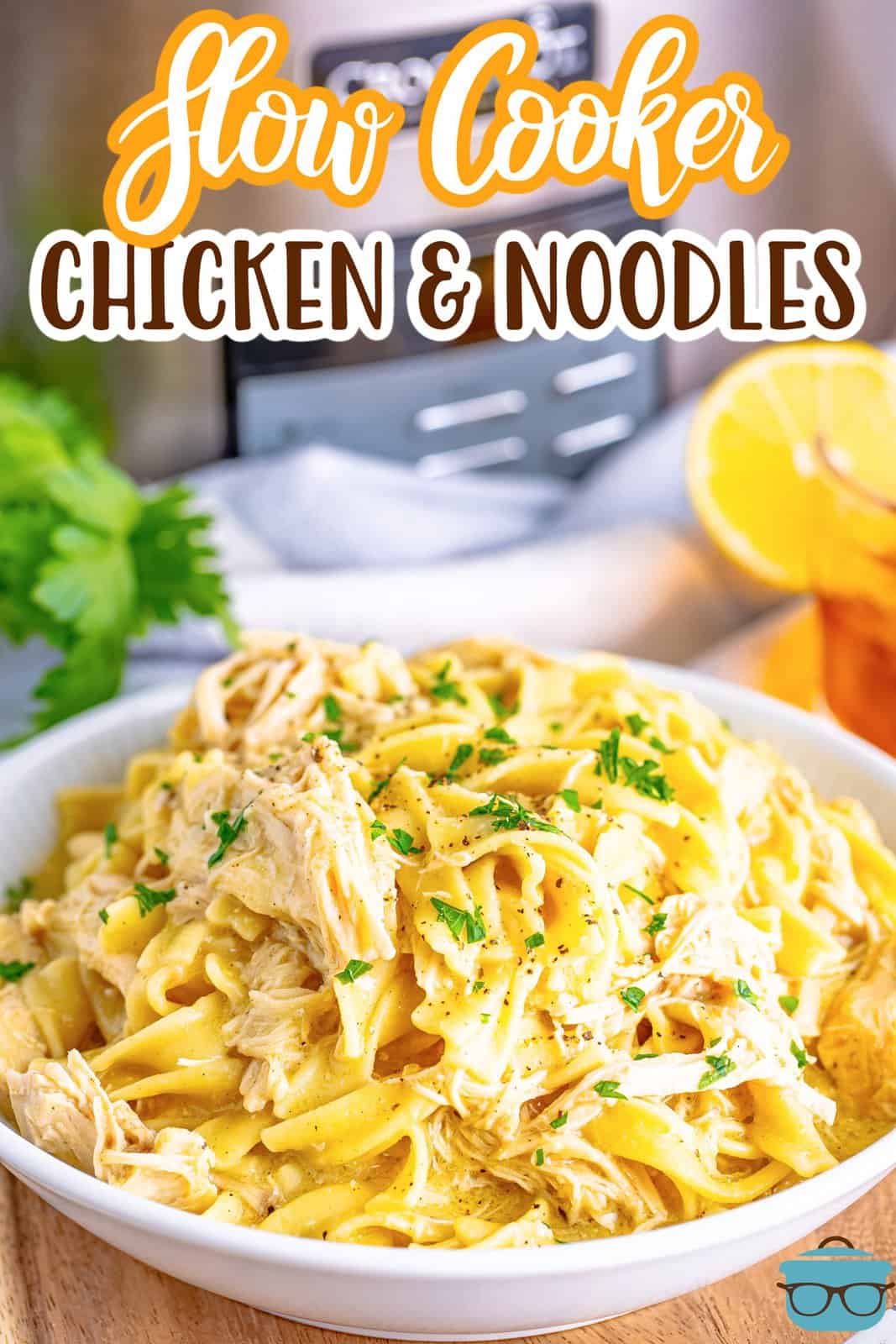 a white bowl filled with shredded chicken and egg noodles with a slow cooker in the background. 