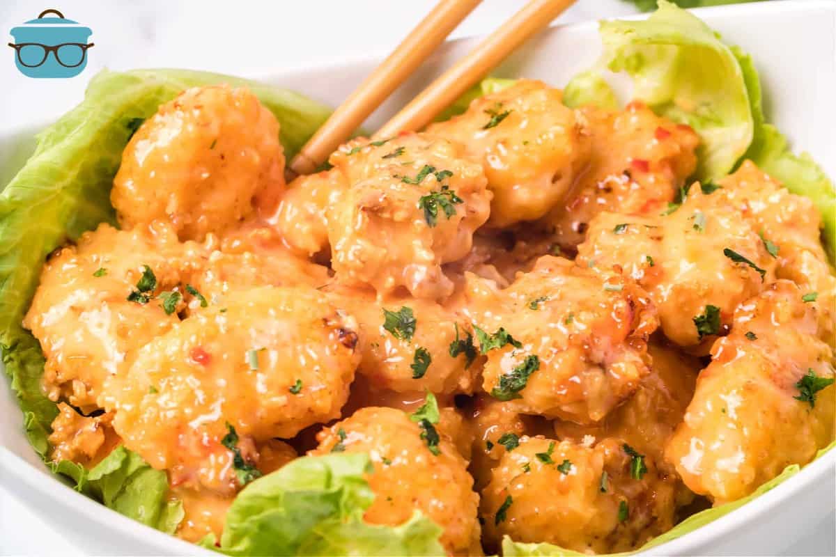 fully cooked Air Fryer Bang Bang Shrimp on a bed of lettuce in a white bowl with chopsticks