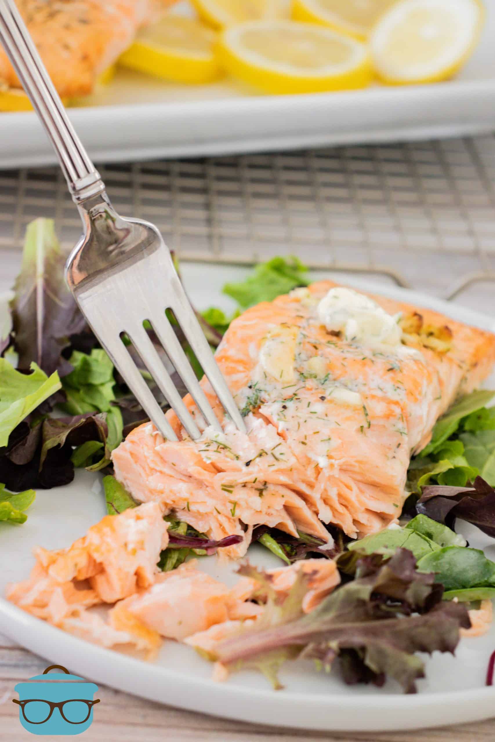 fully cooked salmon on a bed of lettuce with a fork on the salmon slice.