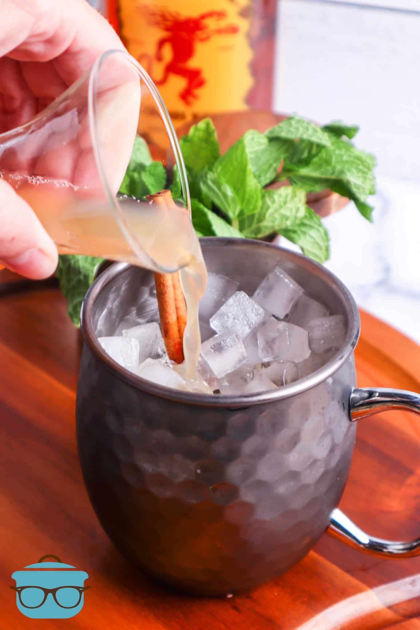 apple cider being poured into a silver Moscow Mule mug.