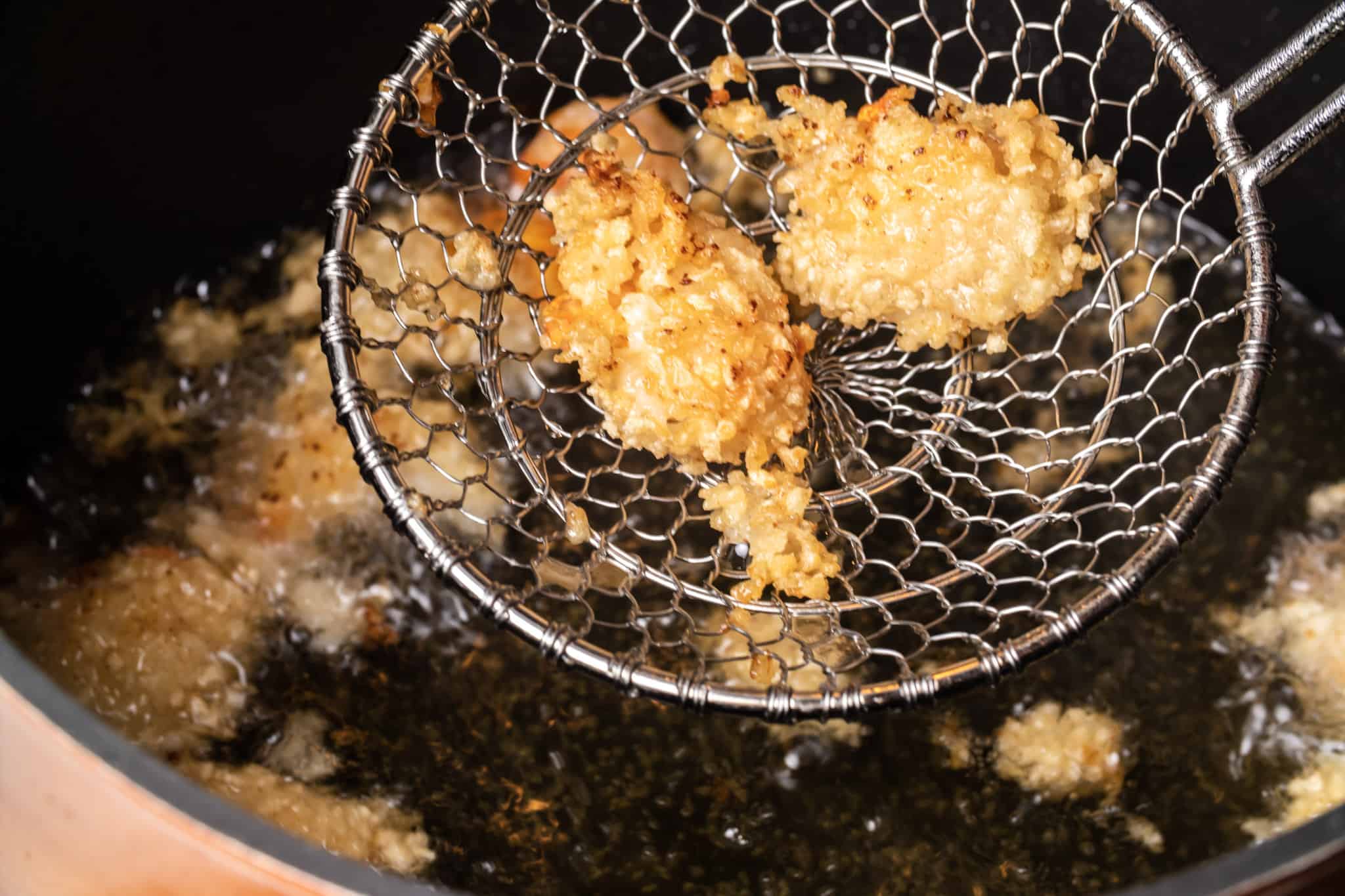 oil fried shrimp in a large pot filled with oil
