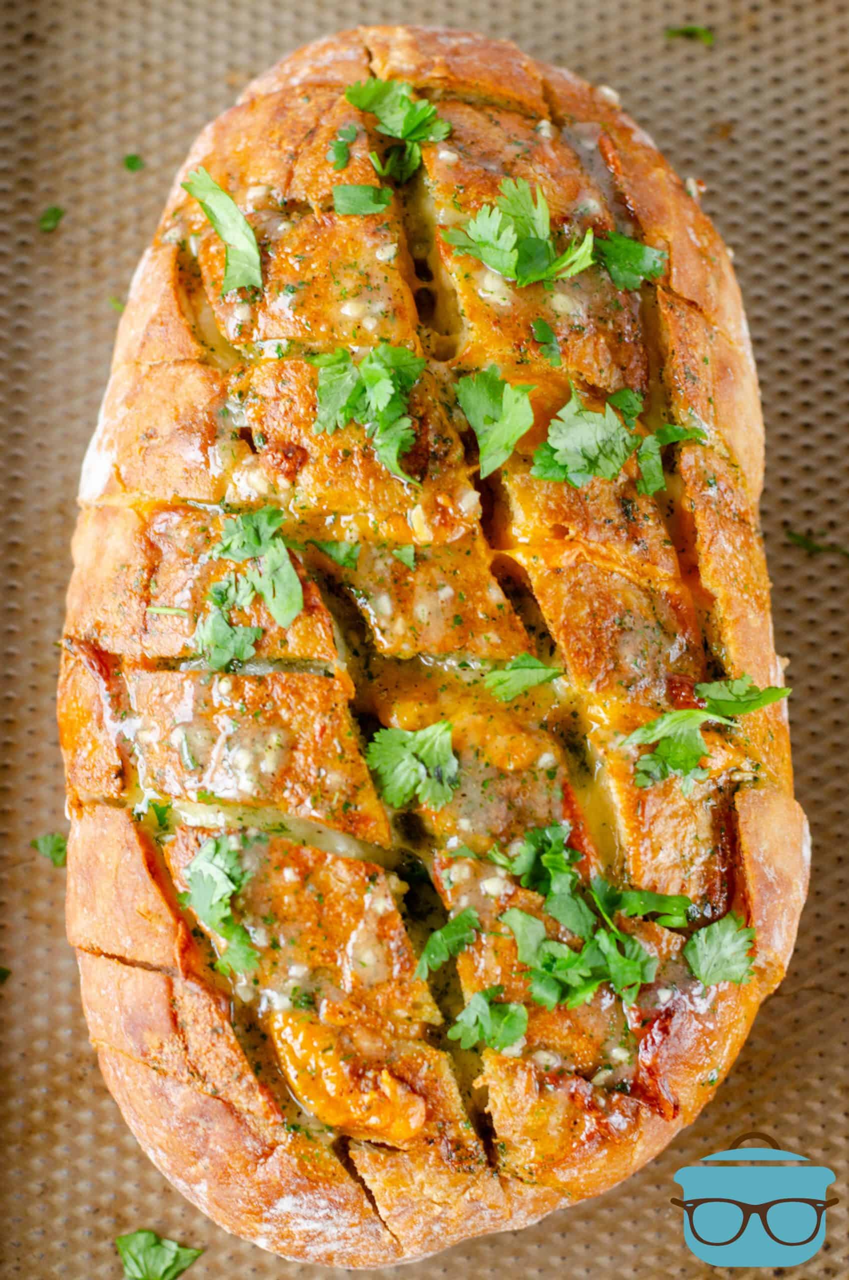 fully baked bacon pull apart bread shown on a baking sheet and topped with fresh chopped parsley. 