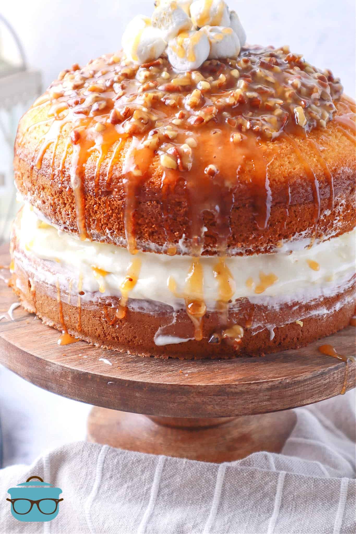 Loaded Sweet Potato Layer Cake shown on a wooden pedestal with pecan glaze drizzling down the sides of the cake.