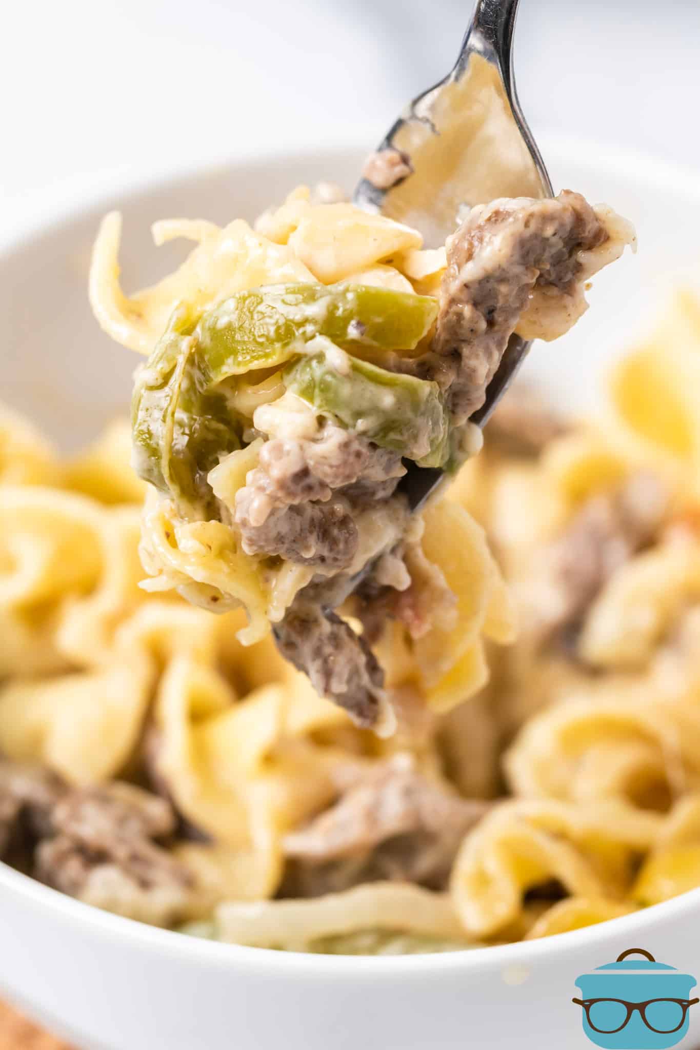 a serving of Philly cheesesteak casserole in a bowl with a forkful of the noodles and beef.