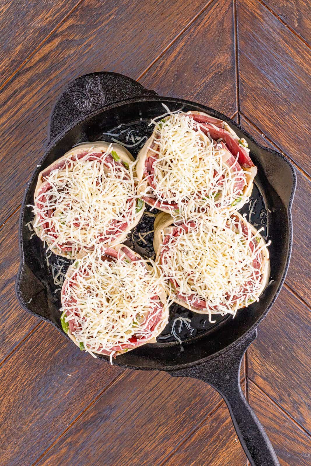 shredded mozzarella cheese on roll ups in cast iron skillet. 