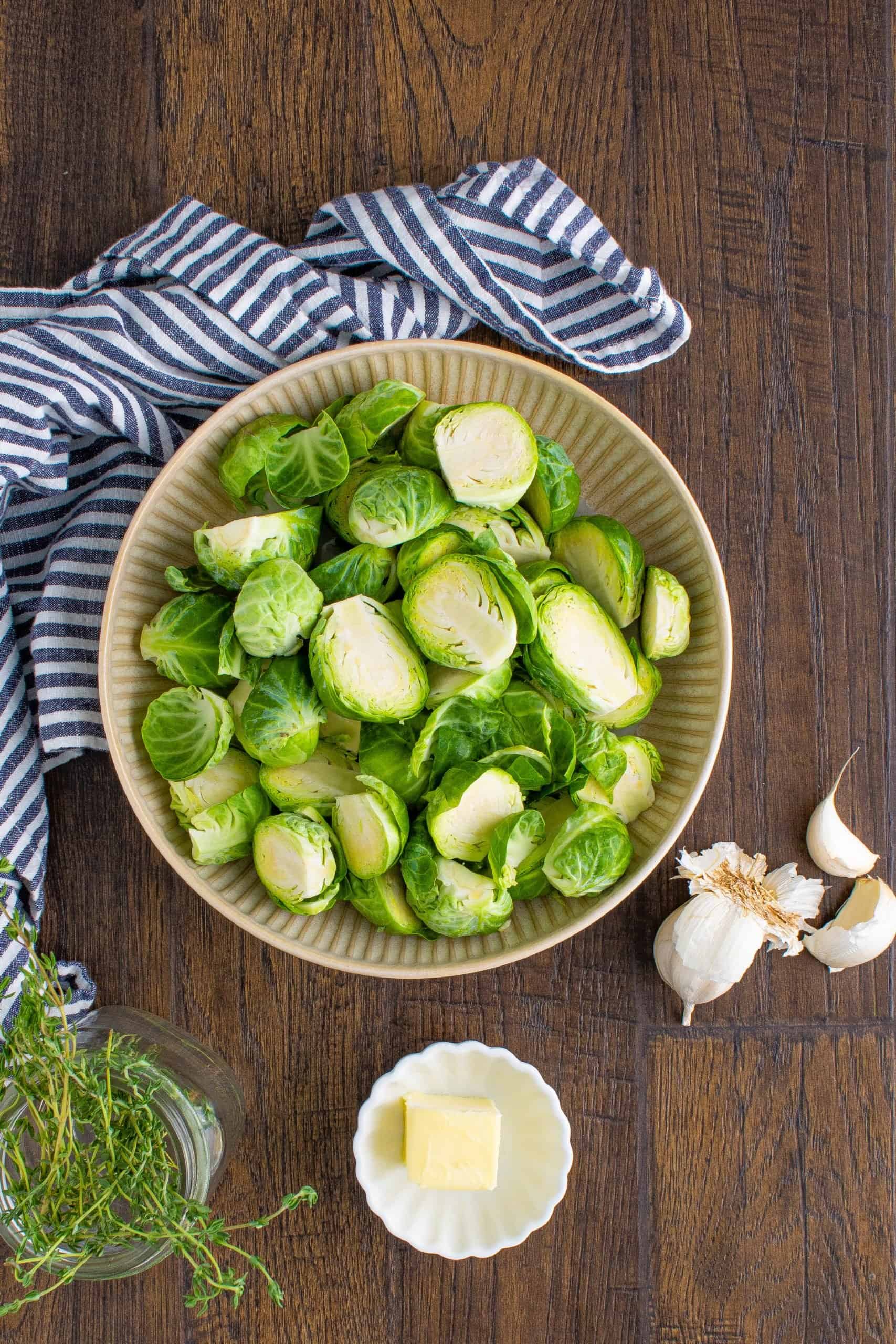 sliced brussel sprouts in a bowl with garlic cloves on the side.
