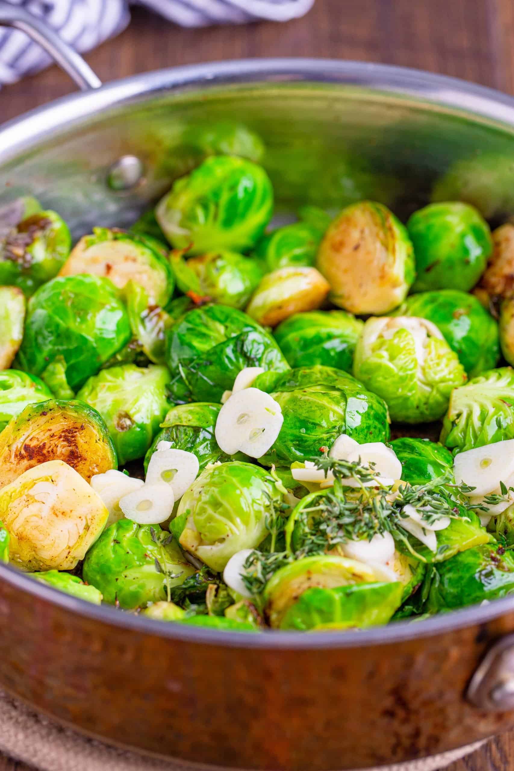sliced brussel sprouts, garlic and thyme added to a large pan.