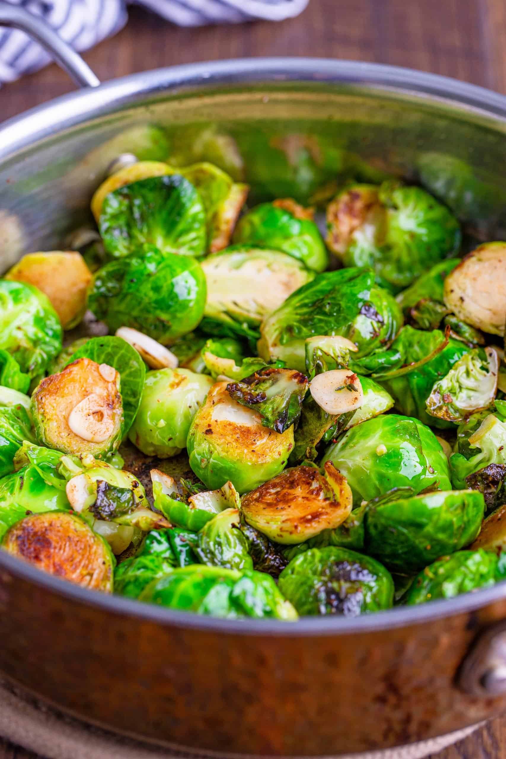 seared brussel sprouts in a large pan with the brussel sprouts getting brown on the sides.