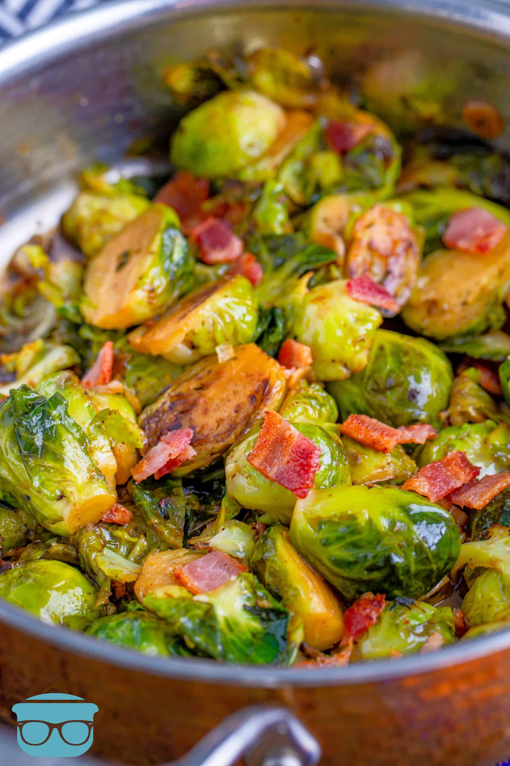 cooked sliced brussel sprouts in a large copper ban sprinkled with chopped bacon.