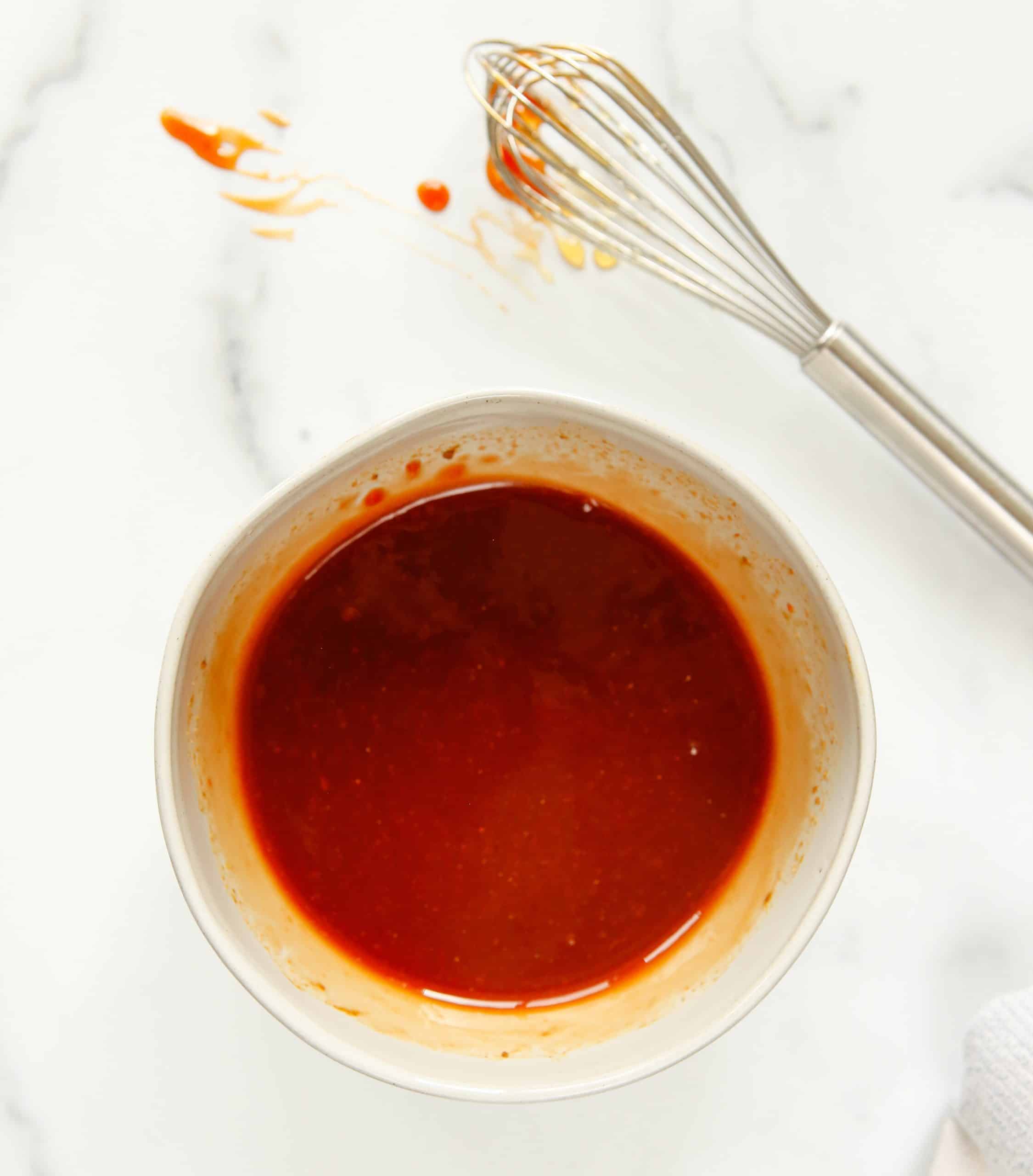 sweet and sour sauce whisked in a small white bowl.
